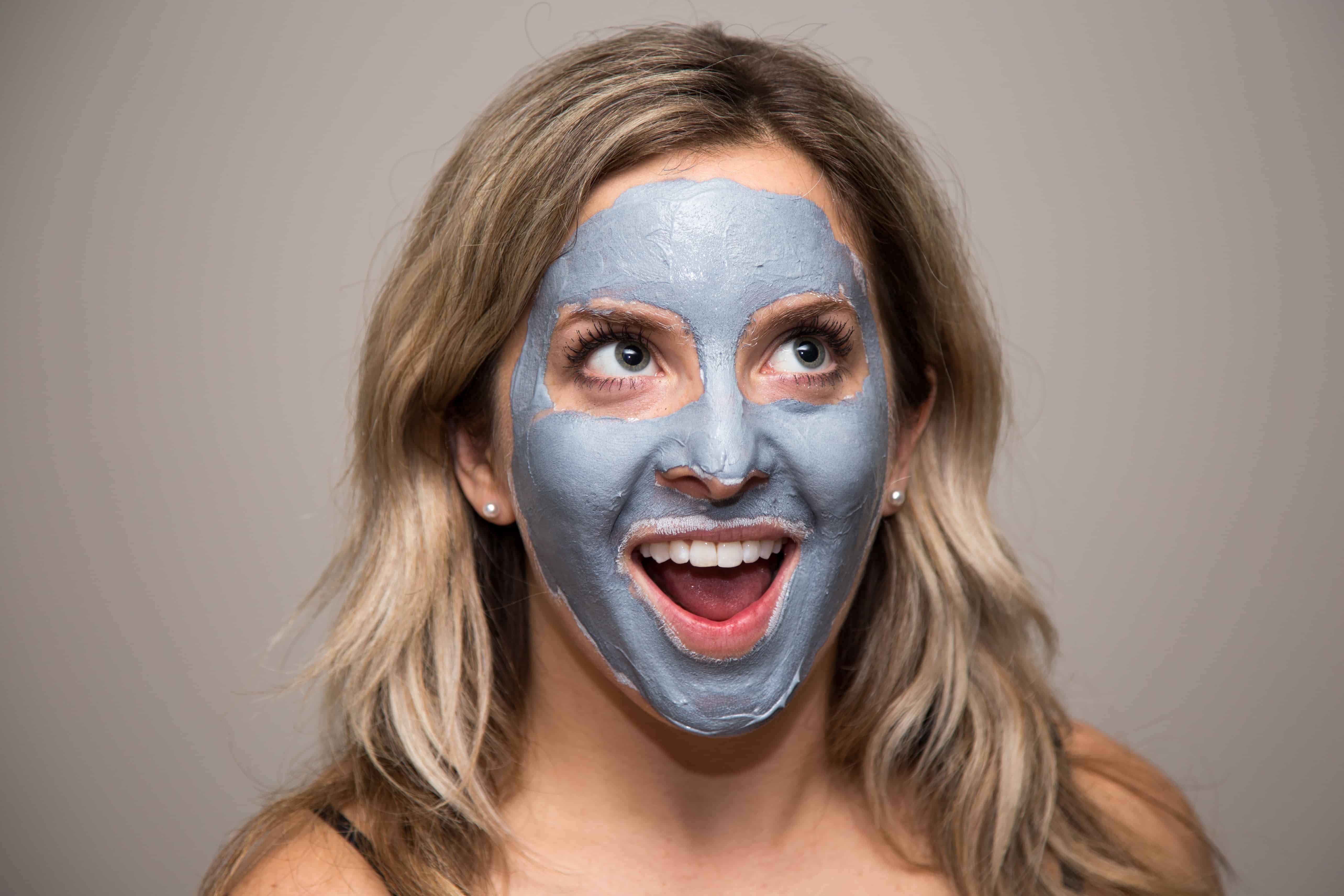 smilende pige iført en naturlig mudder maske facial