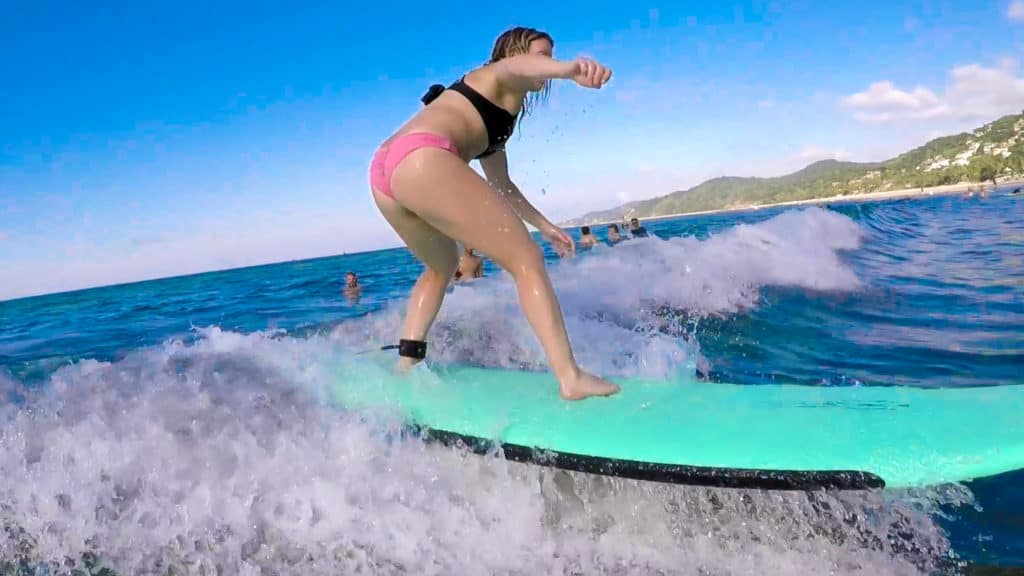 a girl wearing a pink and black bathing suit surfing on a turquoise surf board