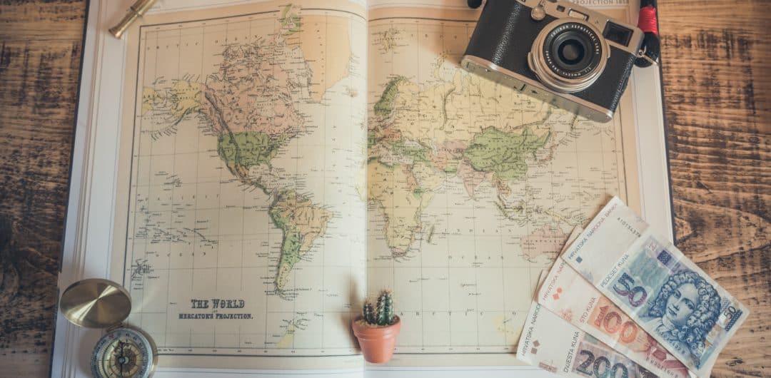 a map, compass and a camera on the table for travel planning