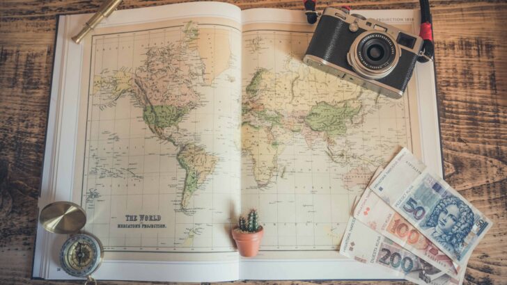 a map, compass and a camera on the table for travel planning