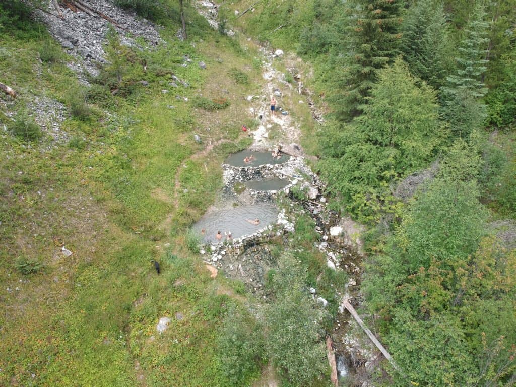 an overhead view of 3 natural hot springs in the middle of a green forest