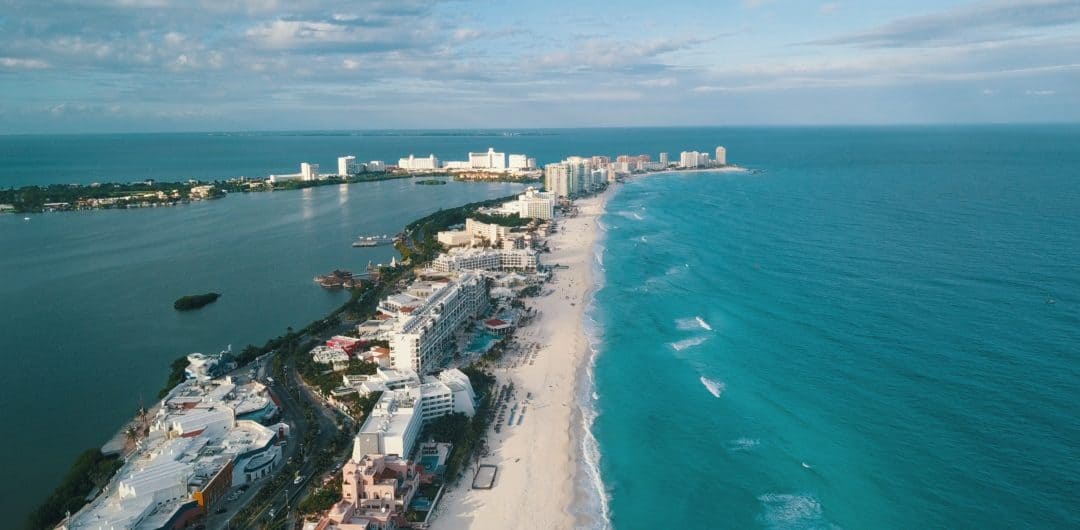 row of hotels along the white sandy beach coastline against turquoise water