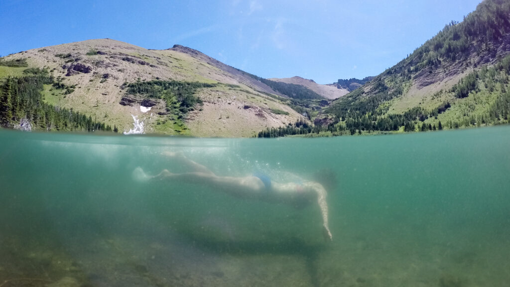 a woman swimming in a clear lake in the mountains
