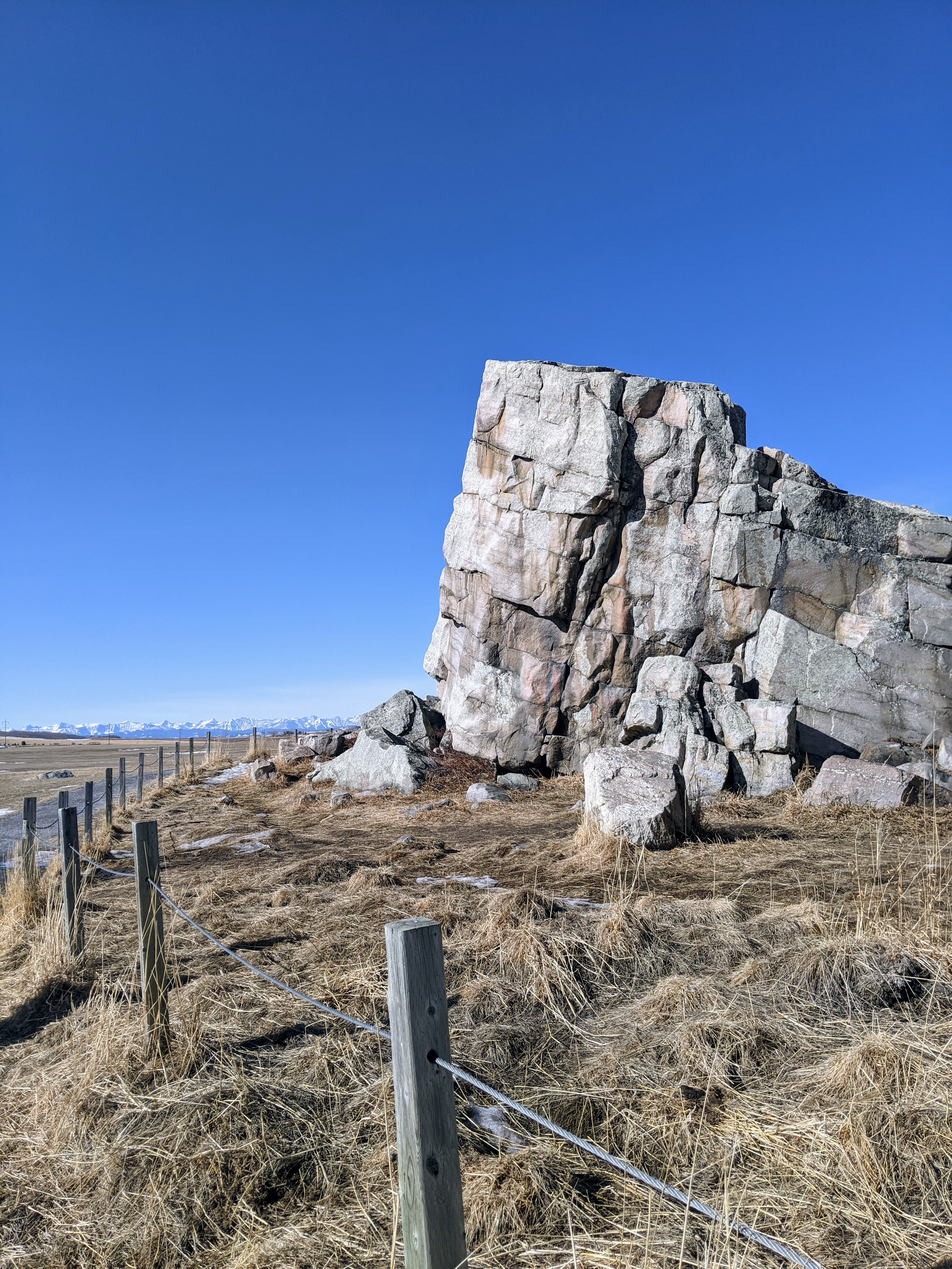 a giant boulder sticks out in the middle of the flat prairie