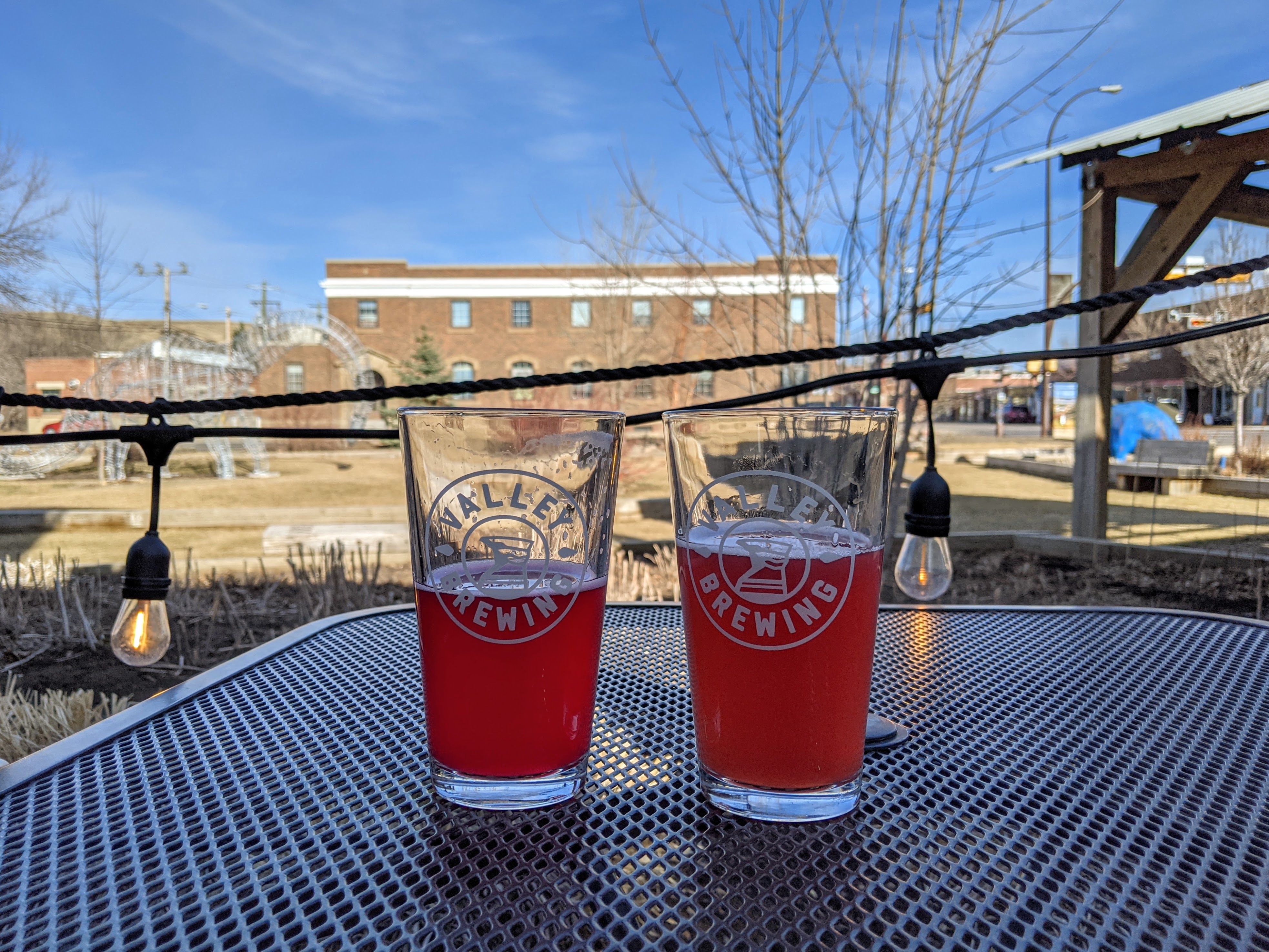 two pints of fruity beer on a patio