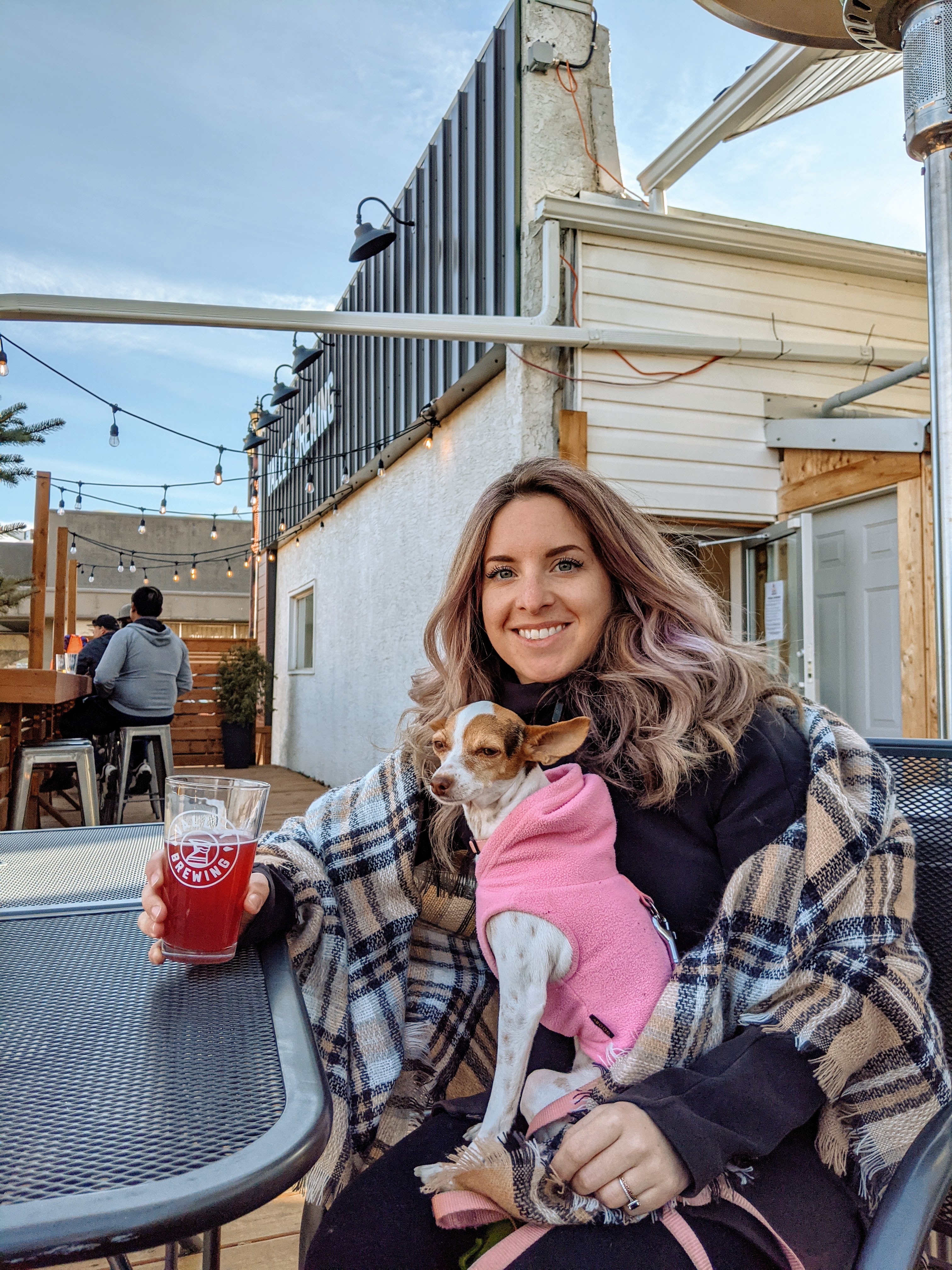 a girl and her small dog having a pint on an outdoor patio