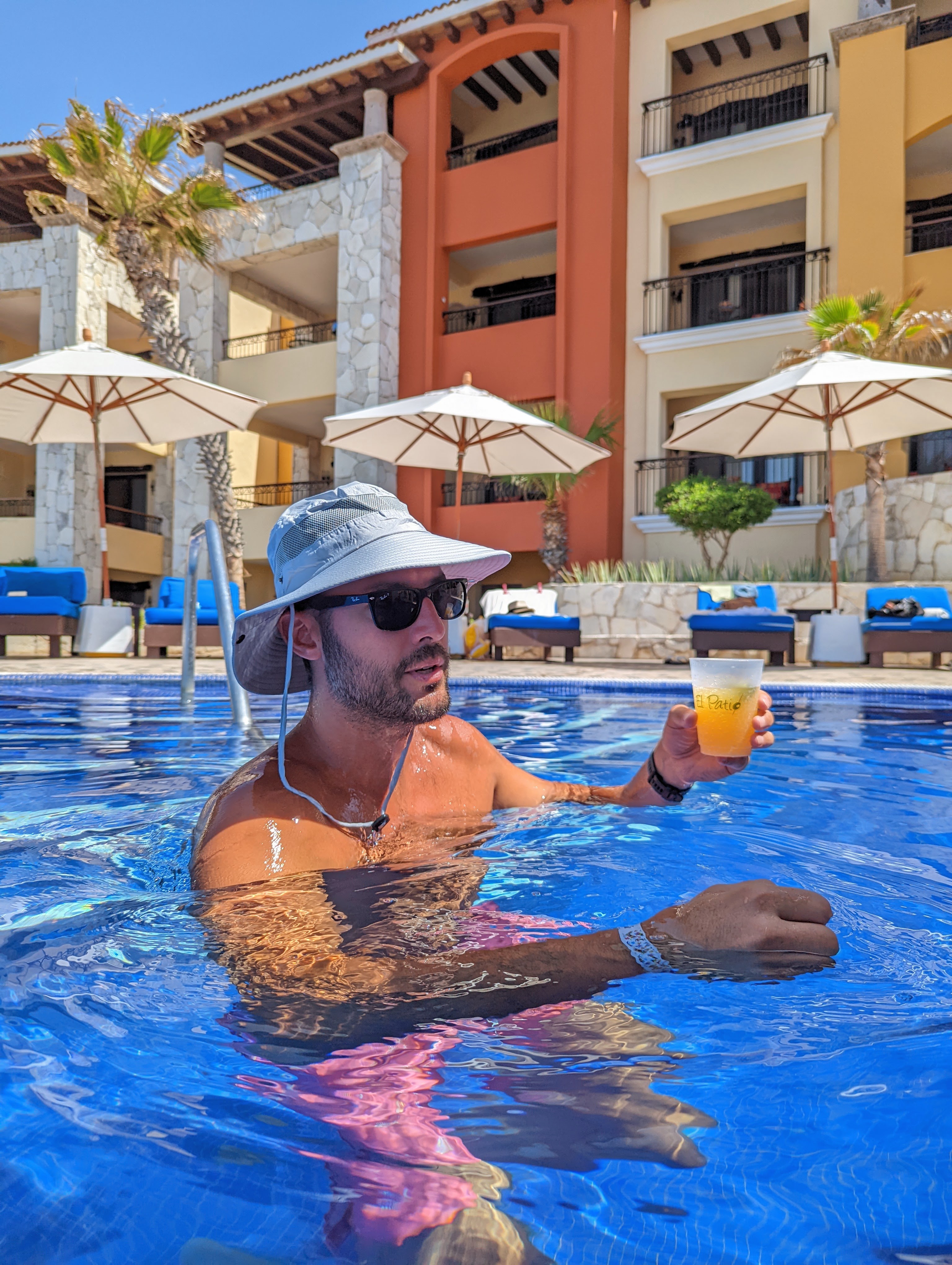 man in pool wearing a wide brim sun hat